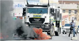  ?? Picture: ALAN EASON ?? TENSE STANDOFF: Police respond to the scene as protesting Samwu workers set tyres alight in Buffalo Street.