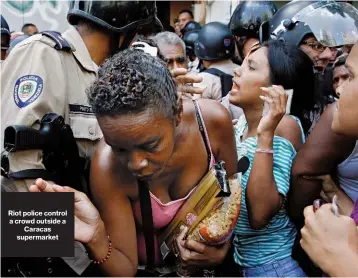  ??  ?? Riot police control a crowd outside a Caracas supermarke­t