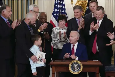  ?? ?? President Joe Biden, seated, looks at Shane Thomas, second from left, husband of the late Marine Corps veteran Kate Hendricks, after signing a bill named after her during an event in the State Dining Room of the White House in Washington, Tuesday, June 7, 2022. Her son Matthew also attends. (AP Photo/susan Walsh)