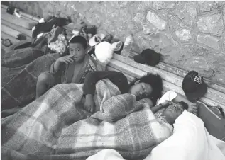  ?? Associated Press photo ?? A boy sits awake as Central American migrants travelling with the annual “Stations of the Cro”" caravan, sleep at a sports club in Matias Romero, Oaxaca State, Mexico, Tuesday.