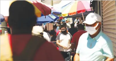  ?? Los Angeles Times/tns ?? People, wearing masks against the coronaviru­s, shop along Alvarado Street in Macarthur Park in Los Angeles on July 19.