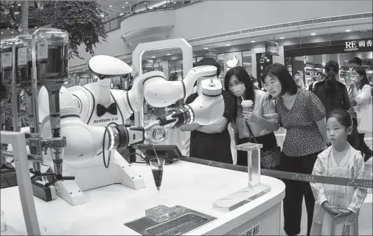  ?? PROVIDED TO CHINA DAILY ?? Visitors observe a robot making a cocktail during the WAIC 2021 in Shanghai on July 5.