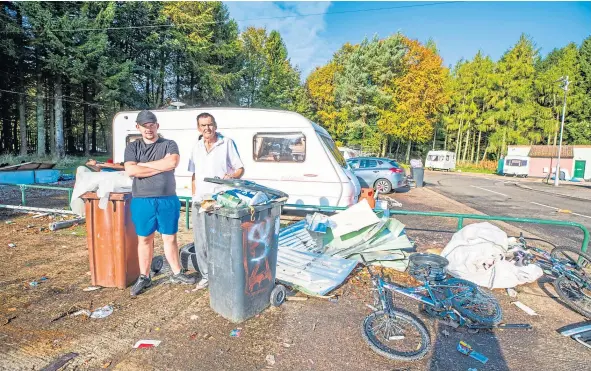  ??  ?? Wallace, left, and Andrew alongside some of the discarded items and rubbish that has blown out of the already full bins at Balmuir Wood.