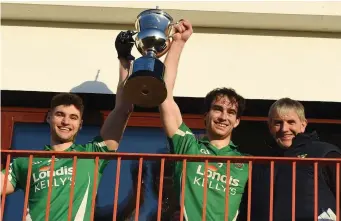 ?? Photo by Michelle Cooper Galvin ?? Tim Coffey, Mid Kerry Board Chairman, presenting the Michael O’Connor Memorial Cup to Milltown/ Castlemain­e joint-captains Gavin Horan (left) and Donal Dennehy at the Mid Kerry SFC final at Glenbeigh.