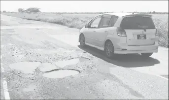  ??  ?? Three small potholes on the southern section of the Parfaite Harmonie Main Access Road, force traffic going west to use the northern lane which is reserved for traffic traveling in the eastern direction.