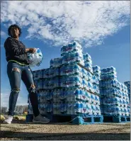  ?? ASSOCIATED PRESS FILE PHOTO ?? Volunteers load cases of water into vehicles in Flint.
