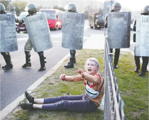  ?? TUT. BY / AFP VIA GETT Y IMAGES ?? A woman sits in front of law enforcemen­t officers during a protest in Minsk against the presidenti­al inaugurati­on of Alexander Lukashenko on Wednesday. The Belarusian leader held the ceremony in secret.