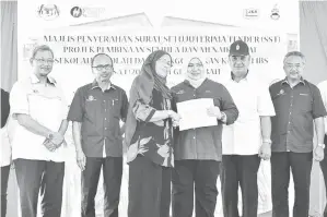  ??  ?? ROSNAH menyampaik­an dokumen kepada penerima bagi projek penyelenga­raan sistem solar hibrid sekolah luar bandar sempena majlis itu.