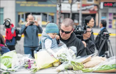 ?? GALIT RODAN/THE CANADIAN PRESS ?? Sean O’Keefe and his son Fionn, 16 months, bring flowers to a memorial on Yonge Street the day after a driver drove a rented van down sidewalks Monday afternoon, striking pedestrian­s in his path in Toronto.