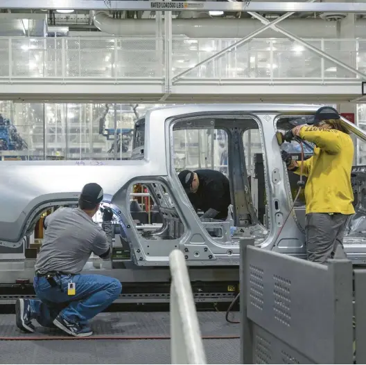  ?? BRIAN CASSELLA/CHICAGO TRIBUNE 2022 ?? Workers assemble R1T trucks April 11 at the Rivian electric vehicle plant in Normal, Illinois. Rivian is one of 13 manufactur­ers that qualify for the tax credit.