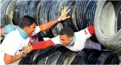  ??  ?? GOT YOU MATE ... Teamwork was vital to complete the obstacles like this, where one has to slip through truck tyres. A participan­t helps his friend cross the obstacle.