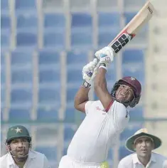  ?? — AFP ?? West Indies’ batsman Leon Johnson (centre) hits a shot as Pakistani wicketkeep­er Sarfraz Ahmed (left) and team-mate Younis Khan look on during the second day of the second Test at the Sheikh Zayed Cricket Stadium in Abu Dhabi on Saturday.