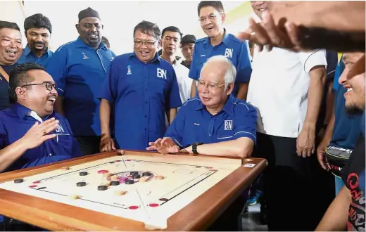  ??  ?? Testing skills: Najib playing carrom as Datuk Shabudin Yahaya (standing on Najib’s right) looks on during a ‘Bersama Rakyat’ programme at Pusat Komersial in Tasek Gelugor.