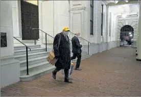  ?? SAM DORAN/SHNS ?? House Speaker Robert DeLeo exits the Statehouse Wednesday night clad in a Bruins cap and accompanie­d by House legal counsel James Kennedy, right. DeLeo silently got into his car without answering questions about whether he would be stepping down.