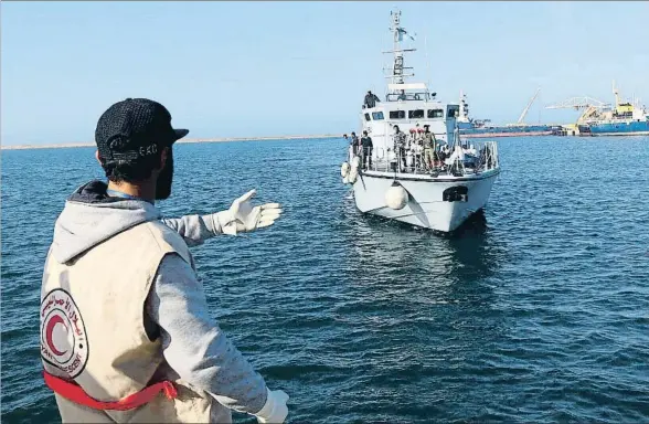  ?? MAHMUD TURKIA / AFP ?? Un trabajador de la Media Luna Roja espera en el puerto de Trípoli la llegada de una embarcació­n con emigrantes, este sábado pasado