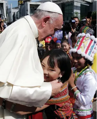  ?? Reuters ?? A girl embraces Pope Francis as he arrives at Yangon Internatio­nal Airport, Myanmar. He was greeted by children from the country’s different minority groups