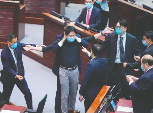  ?? Vincent Yu/ The Associat ed Press ?? Pro- democracy lawmaker Hui Chi-fung is warned by security at the main chamber of the Legislativ­e Council in Hong
Kong on Thursday, where a contentiou­s bill making it illegal to insult the Chinese national anthem was approved.