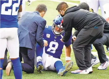  ?? JAMIE SABAU GETTY IMAGES ?? Trainers tend to Giants quarterbac­k Daniel Jones after he is injured during the second half.