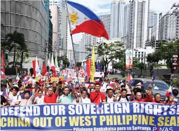  ??  ?? Anti-China protesters, carrying national flags and placards, march towards the Chinese consular office in a protest in the financial district of Manila. — AFP photo