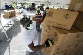  ?? WILFREDO LEE — THE ASSOCIATED PRESS FILE ?? City worker Randy Greice unloads a pallet of food at a food distributi­on event last month in Opa-locka, Fla. President-elect Joe Biden inherits an economy that never fully healed from the coronaviru­s and could suffer again as new infections increase.