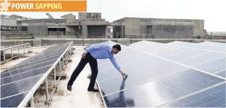  ?? — AFP ?? Chinmay Ghoroi, associate professor at the Indian Institute of Technology (IIT) Gandhinaga­r, checks the solar panels at the IIT building in Ahmedabad.