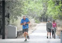  ??  ?? Steve Arnold, center, checks his time on a 6mile run in Phil Hardberger Park.