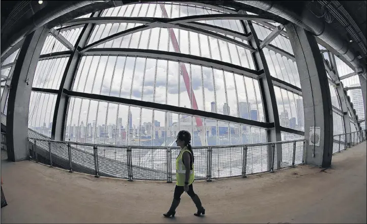  ?? PHOTOS BY CURTIS COMPTON / CCOMPTON@AJC.COM ?? A worker passes by a floor-to-ceiling window offering a view of the city during a tour inside Mercedes-Benz Stadium.