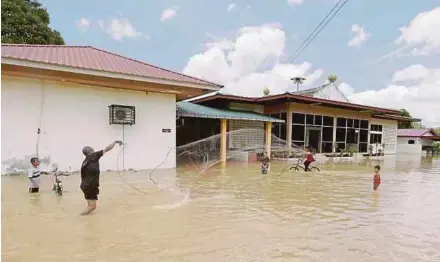  ?? PIC BY SHAHRIZAL MD NOOR ?? Villagers in Derang, Pokok Sena, catching fish in the floodwater­s yesterday.