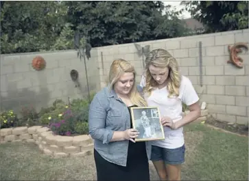  ?? Photograph­s by Patrick T. Fallon For The Times ?? HALIE GRIFFIN, left, and her sister Katie Howe hold a photograph of their grandmothe­r, Julie Shepherd, who died after being infected with a severe form of West Nile virus called neuroinvas­ive disease.