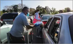  ?? RAY CHAVEZ — STAFF PHOTOGRAPH­ER ?? Volunteer Pedro Salas offers hot meals to clients while they wait their turn to get food supplies during a drive-thru food distributi­on at the Our Lady of Refuge parking lot in San Jose on April 5.