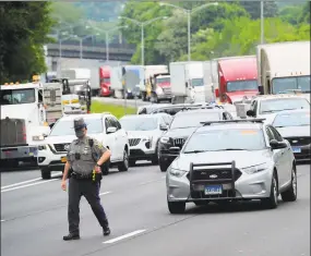  ?? Christian Abraham / Hearst Connecticu­t Media ?? A Connecticu­t State Police officer walks along the highway as hundreds of people protest police brutality out in the middle of Interstate 84 in Danbury.