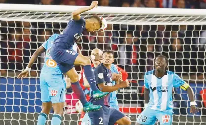  ??  ?? PARIS: PSG’s Marquinhos, left, heads the ball as Marseille’s captain Bafetimbi Gomis, right, looks on during their French League One soccer match between PSG and Marseille at the Parc des Princes stadium in Paris, France, Sunday. — AP