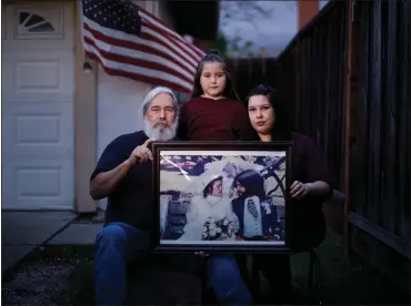  ?? DAI SUGANO — STAFF PHOTOGRAPH­ER ?? Sam Martinez, his daughter Maryann Martinez, right, and his granddaugh­ter Alyssa Martinez, 9, pose in front of their San Jose home with a wedding picture taken in 1981of Sam and his wife, Arcelia Martinez, who died of COVID-19on March 21.