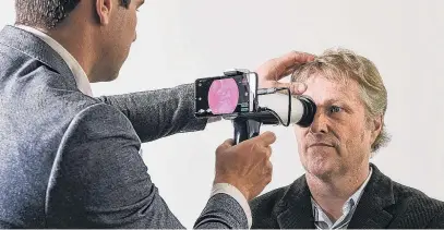  ?? PHOTO: SUPPLIED ?? Closer look . . . Dr Ben O’Keeffe (left) examines a patient using one of oDocs Eye Care’s devices attached to a smartphone.
