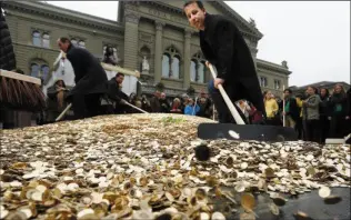  ??  ?? Swiss backers of a minimum universal income spread out coins at a recent rally in Bern. A whopping 76 per cent of voters were against the proposal.