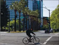  ??  ?? A cyclist rides along West San Carlos Street past Almaden Boulevard in downtown San Jose on April 21. Team San Jose’s goal is to be “more community-minded,” focusing on local and regional marketing, LaFortune says.