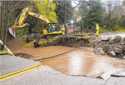  ?? NIC COURY AP ?? Crews assess storm damage in Soquel in Santa Cruz County on Friday after heavy rains washed out part of a road near Bates Creek. The San Lorenzo River crested Friday morning, prompting evacuation orders for nearby areas because of flooding.