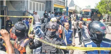  ??  ?? Members of Indonesia’s Densus 88 counter-terror police squad cordon an area as they conduct a raid on the residence of a family suspected of taking part in recent suicide bombings in Surabaya. — AFP photo