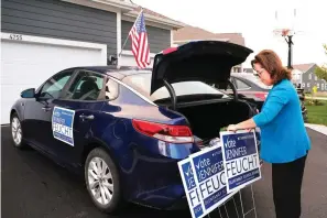  ?? The Associated Press ?? Jennifer Feucht, candidate for Olentangy Local Board of Education, delivers campaign flyers and yard signs to Brad and Tina Krider on Thursday in Westervill­e, Ohio. Across Ohio and the nation, parental protests over social issues like mask mandates, gender-neutral bathrooms, teachings on racial history, sexuality and mental and emotional health are being leveraged into school board takeover campaigns.