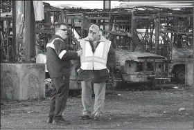  ?? File Photo/NWA Democrat-Gazette/DAVID GOTTSCHALK ?? Ozark Regional Transit employees look at the remains of destroyed buses Jan. 10, 2017, in Springdale. Twenty buses were destroyed by fire.