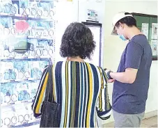  ?? — AFP file photo ?? Residents get free reusable face masks from a vending machine by scanning their identifica­tion card, set up by the government as part of the effort to halt the spread of the Covid-19 coronaviru­s, at a community centre in Singapore.