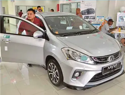  ?? PIC BY FAIZ ANUAR ?? People checking out the recently-launched Perodua Myvi at the company’s showroom in Klang. The company is cautiously confident of achieving the 202,000-unit sales target for last year, backed by the new model.