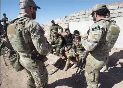  ?? RYAN REMIORZ, THE CANADIAN PRESS ?? Canadian special forces soldiers speak with Peshmerga fighters at an observatio­n post in northern Iraq. The federal government says the Canadian military will remain in Iraq for at least two more years as part of an internatio­nal coalition.