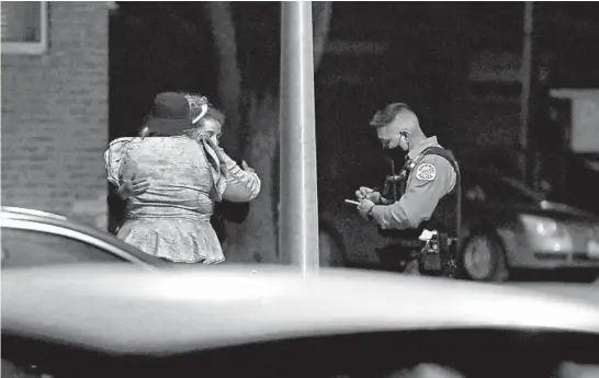  ??  ?? Two women comfort each other while talking with a police officer after they were carjacked in front of one of the women’s homes Calumet Heights on March 9.