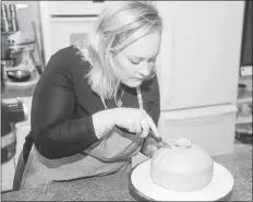  ?? MITCH MACDONALD/THE GUARDIAN ?? Chelsea Willis cuts into the multi-layered Swedish Princess Cake.