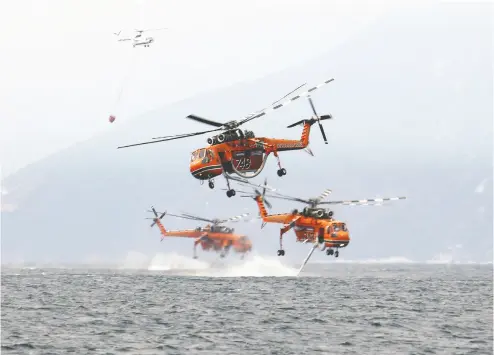  ?? NICOLAS ECONOMOU / REUTERS ?? Firefighti­ng helicopter­s collect water Tuesday near the village of Pefki, on the island of Evia, Greece.