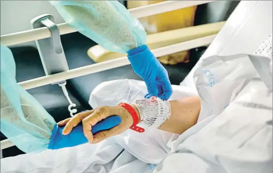  ?? ÀLEX GARCIA ?? Una profession­al d’infermeria de l’hospital de Sant Pau de Barcelona atén a una malalta afectada de covid