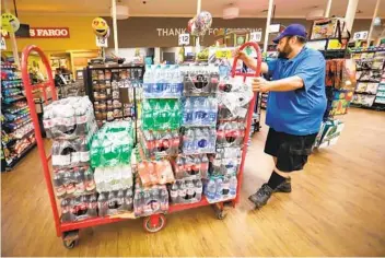  ?? HOWARD LIPIN PHOTOS U-T ?? Chris Nahhar, a Reyes Coca-cola Bottling merchandis­er, pulls a cart full of soft drinks while restocking the Ralphs supermarke­t in the La Jolla Square shopping center, early Thursday morning.