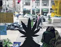  ?? Kena Betancur / Getty Images ?? People pass in front of the Weed World store on Wednesday in New York. Gov. Andrew M. Cuomo signed legislatio­n legalizing recreation­al marijuana on Wednesday.