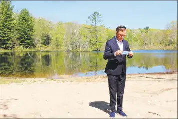  ?? Pat Eaton-Robb / Associated Press ?? Gov. Ned Lamont prepares to put on a face mask at Gay City State Park in Hebron on Thursday. The governor held his daily COVID-19 briefing for the media at the park in advance of the Memorial Day weekend.